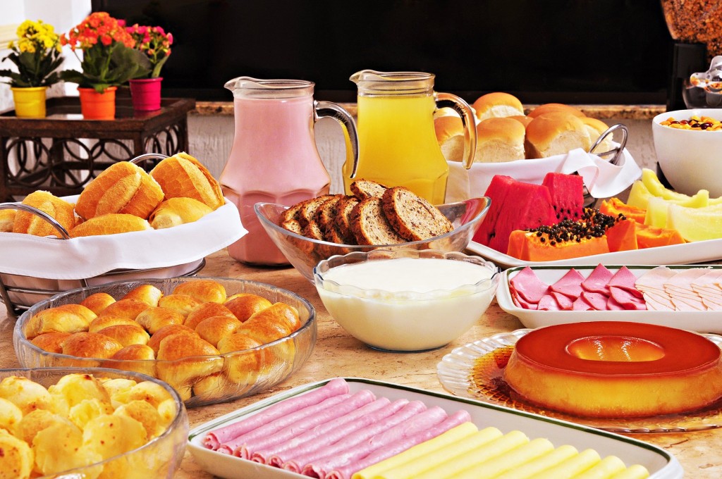 mesa-de-café-da-manhã-com-frutas-pães-sucos-bolos-e-iogurt